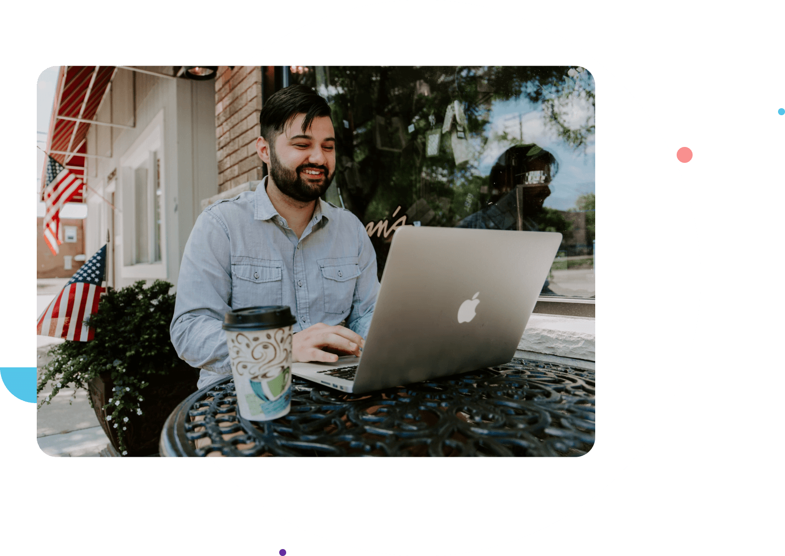 The man is sitting at the table using a laptop.