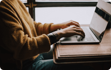 Person sitting at table typing on laptop
