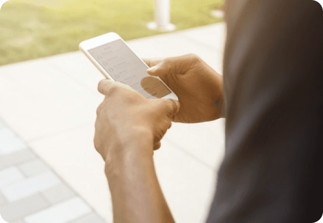 Person's hands using cell phone standing outside