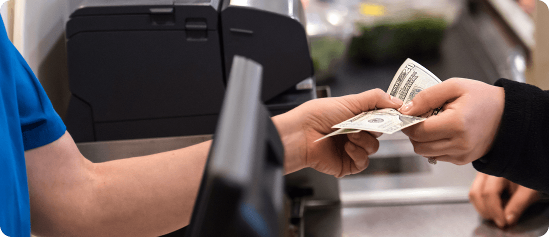 Person handing money to cashier at grocery store