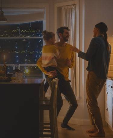 A couple standing with a child in the dining room.