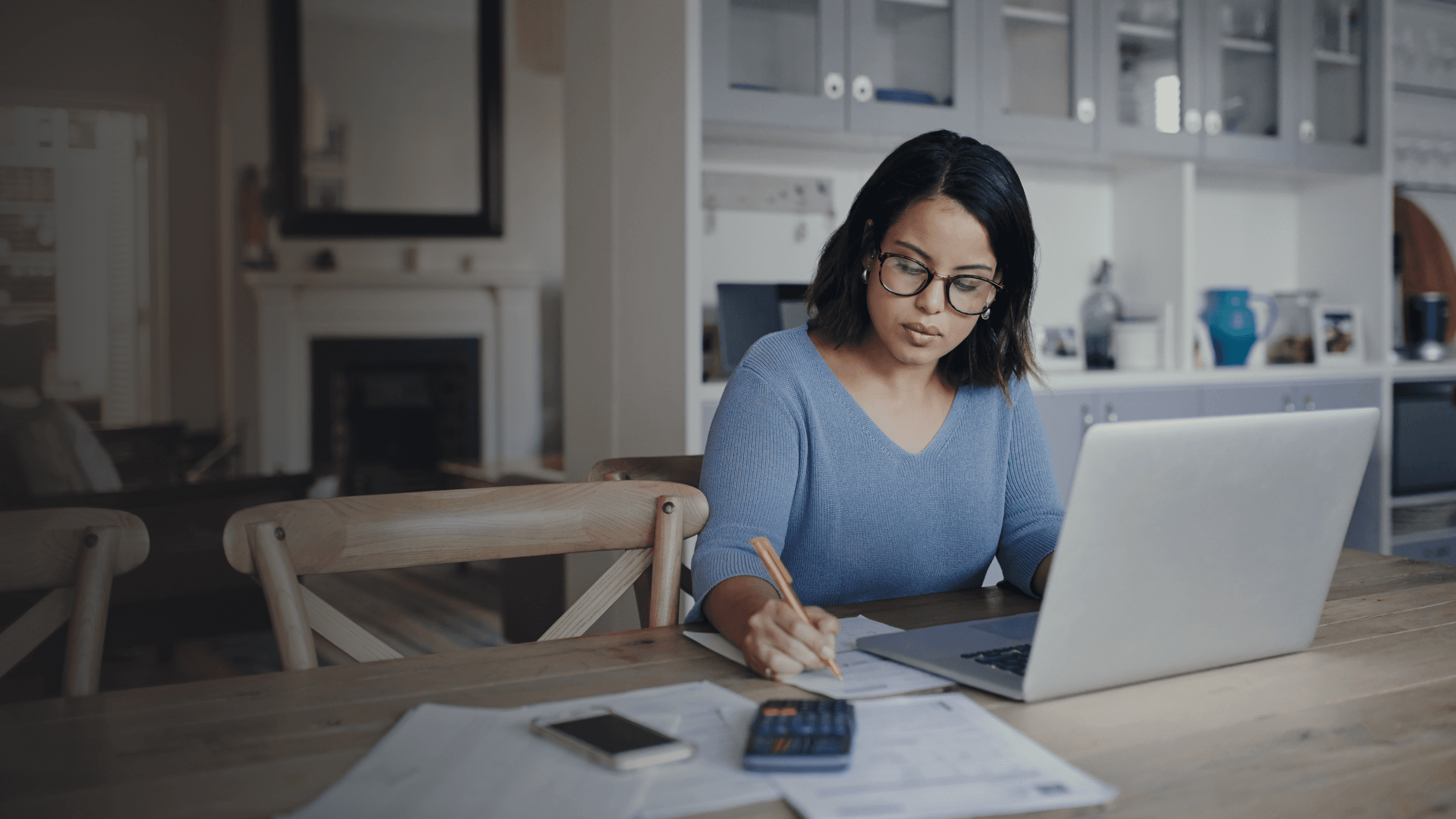 The girl is sitting and working with a pen.