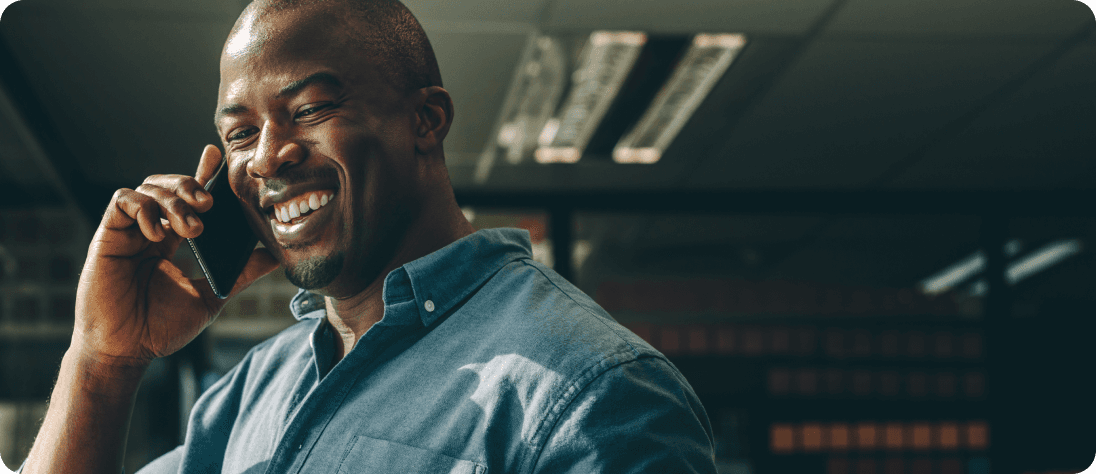 Smiling man using cell phone in darkly lit room