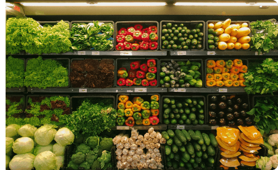 grovery store shelves filled with zucchini, bell peppers, lettuce and other vegetables
