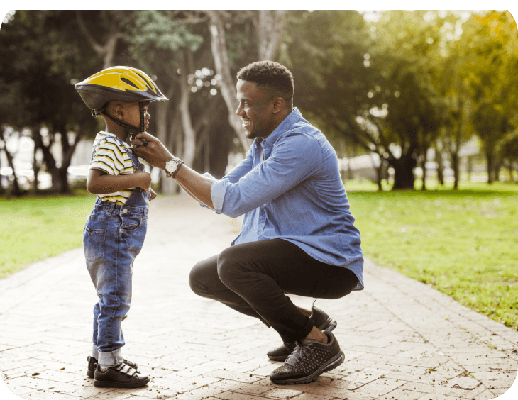 The man is sitting with the child and preparing him for cycling.